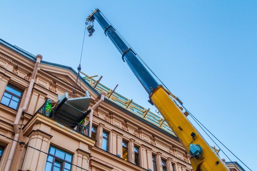 A Crane is Lifting a Piece of Metal on Top of a Building — Trucking Crane Trucks in Warana, QLD