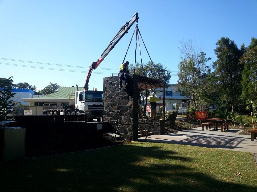 A Crane is Lifting a Large Stone Structure in a Park — Trucking Crane Trucks in Warana, QLD