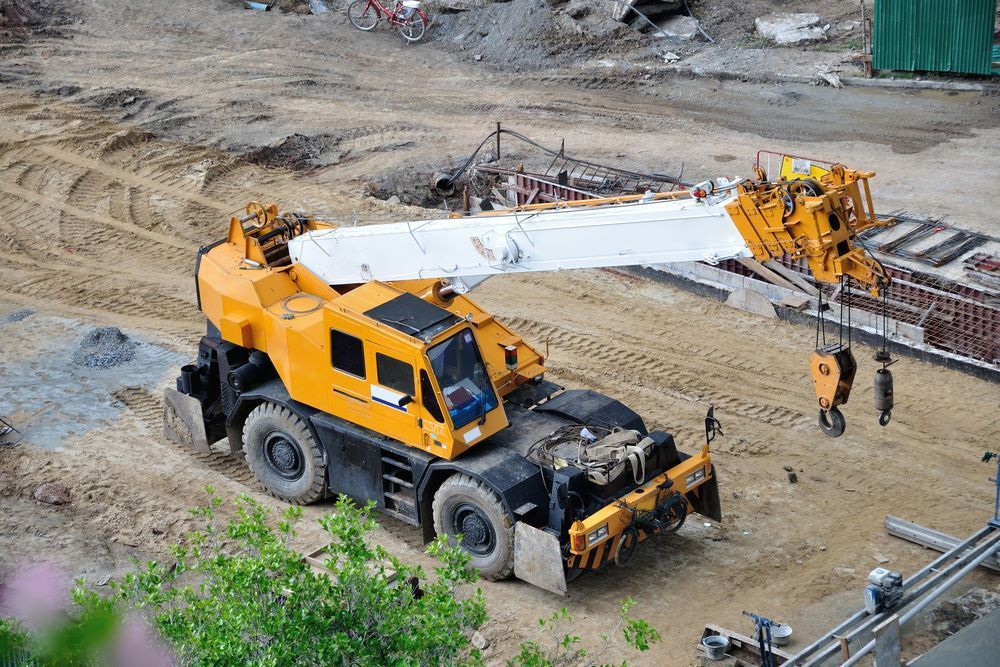 A Large Yellow Crane is Sitting on Top of a Dirt Field — Trucking Crane Trucks in Maroochydore, QLD