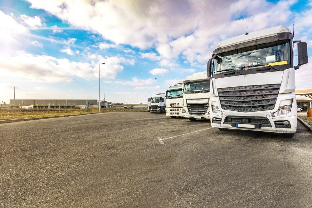 A Row of White Semi Trucks Are Parked in a Parking Lot — Trucking Crane Trucks in Maroochydore, QLD