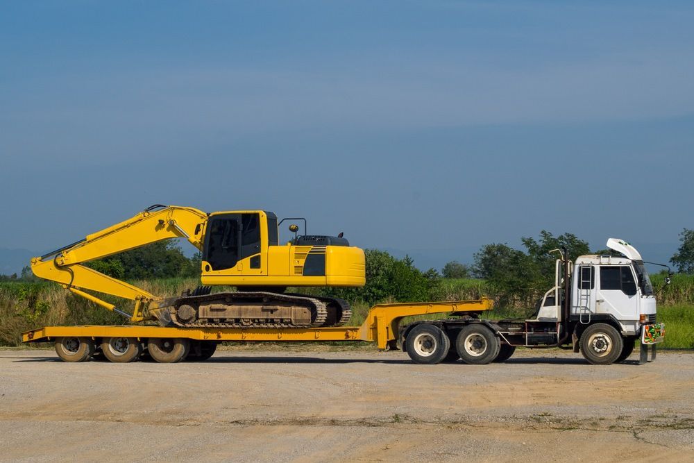 A Yellow Excavator is Being Transported on a Flatbed Trailer — Trucking Crane Trucks in Maroochydore, QLD
