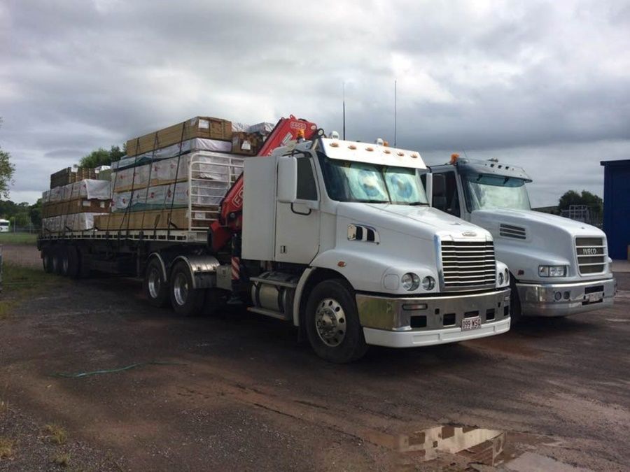 Two Semi Trucks Are Parked Next to Each Other on a Dirt Road — Trucking Crane Trucks in North Lakes, QLD