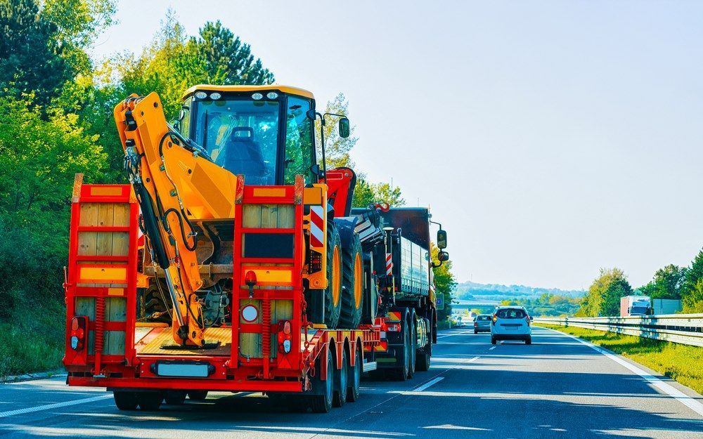 A Tractor is Driving Down a Highway on a Trailer — Trucking Crane Trucks in Warana, QLD