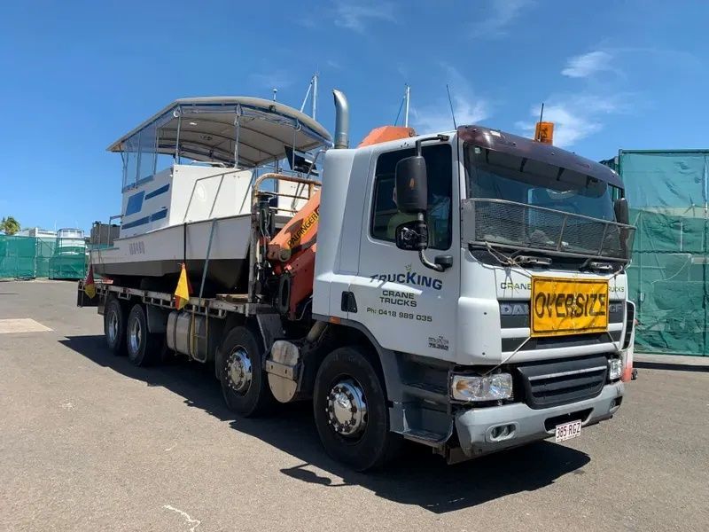 A Truck is Carrying a Boat on the Back of It — Trucking Crane Trucks in Warana, QLD