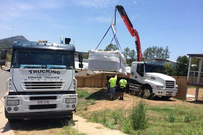 A Truck With the Word Trucking on the Side is Being Lifted by a Crane — Trucking Crane Trucks in Warana, QLD