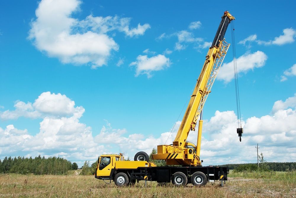 A Yellow Crane is Sitting on Top of a Truck in a Field — Trucking Crane Trucks in North Lakes, QLD