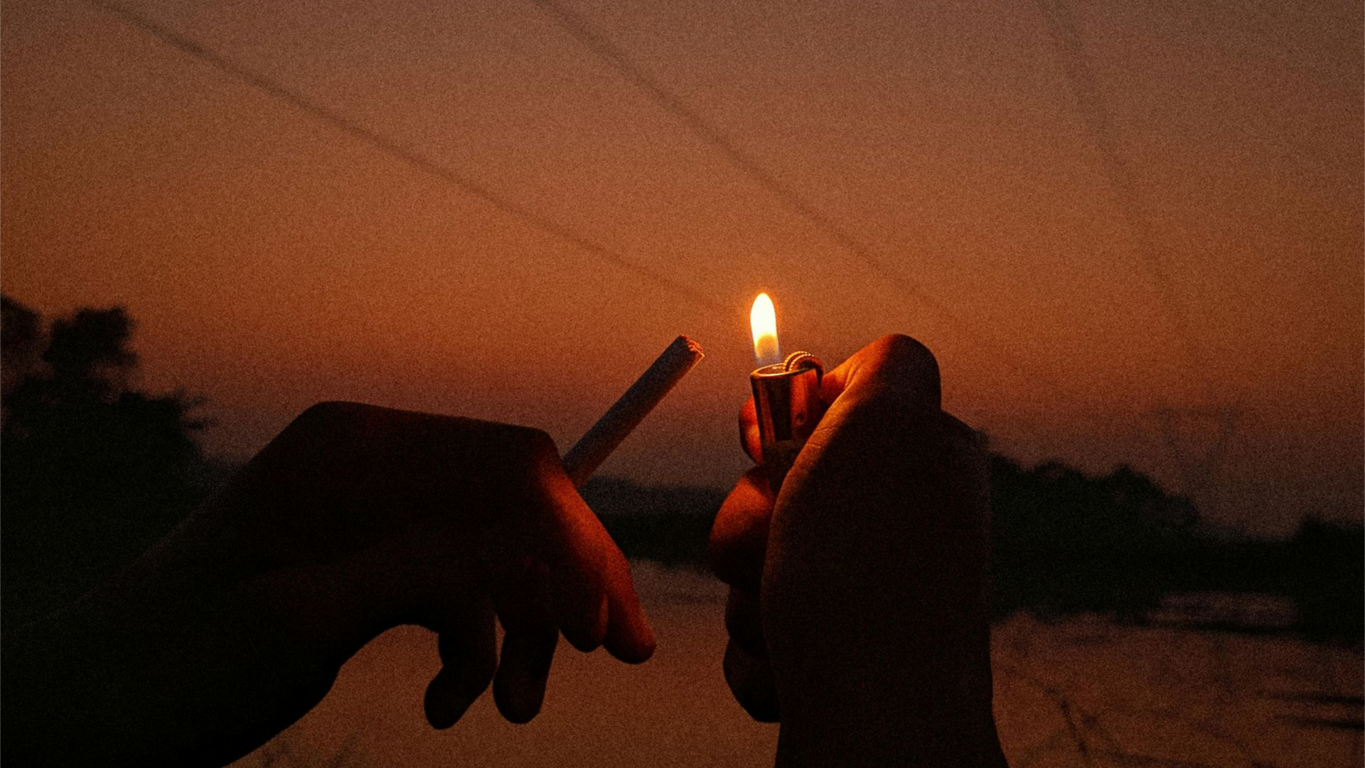 Silhouette of pair of hands lighting a cigarette