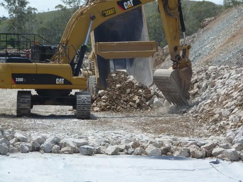 A Cat Excavator Is Digging in A Pile of Rocks — Mike Barlow Earthmoving Pty Ltd in Rockhampton, QLD