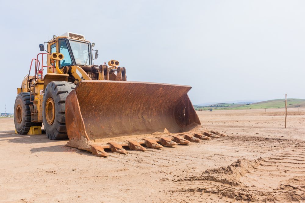 Yellow Bulldozer With a Large Front Blade on a Sandy Construction Site Under a Pale Sky — Mike Barlow Earthmoving Pty Ltd in Rockhampton, QLD