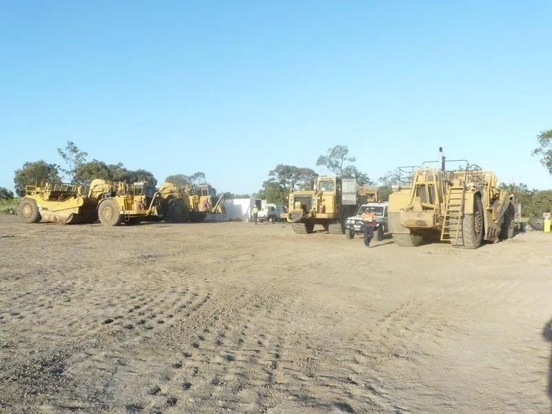 Excavator Parked In A Row On A Dirt Field — Mike Barlow Earthmoving Pty Ltd in Rockhampton, QLD