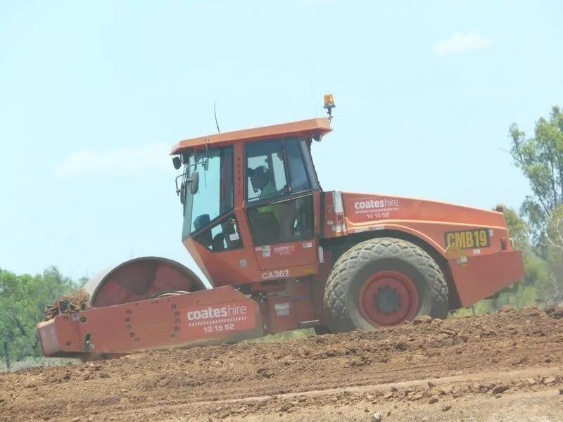 Red Earthmoving Rolling Across Earth Field — Mike Barlow Earthmoving Pty Ltd in Rockhampton, QLD