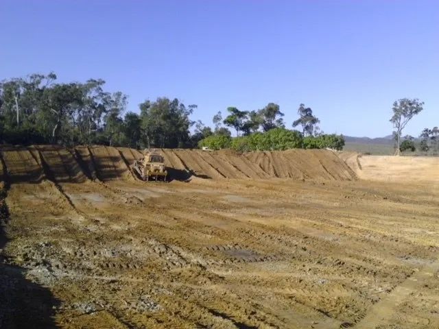 A Large Dirt Field with Trees in The Background — Mike Barlow Earthmoving Pty Ltd in Rockhampton, QLD