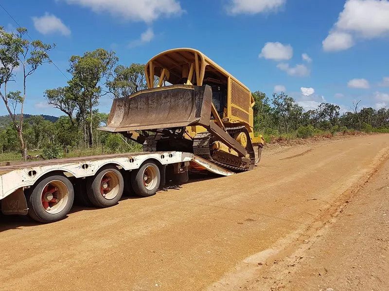 Yellow Bulldozer Is Being Loaded On The Towing Truck — Mike Barlow Earthmoving Pty Ltd in Rockhampton, QLD