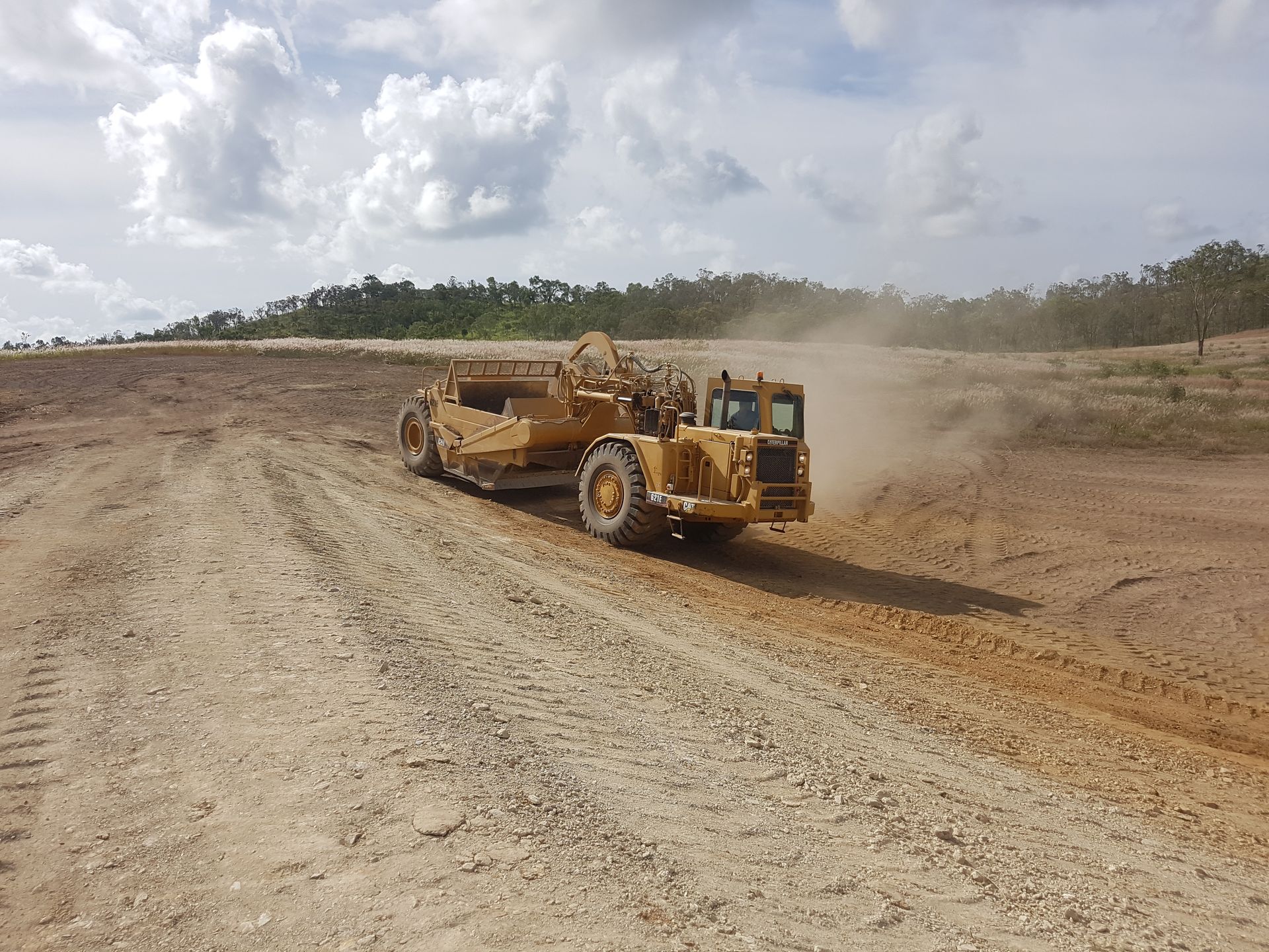 A Dirt Road Going Through a Field with Trees in The Background — Mike Barlow Earthmoving Pty Ltd in Yeppoon, QLD