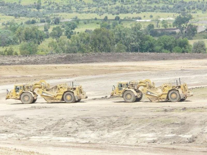 Two Yellow Excavators Rolling Across a Dirt Field— Mike Barlow Earthmoving Pty Ltd in Rockhampton, QLD