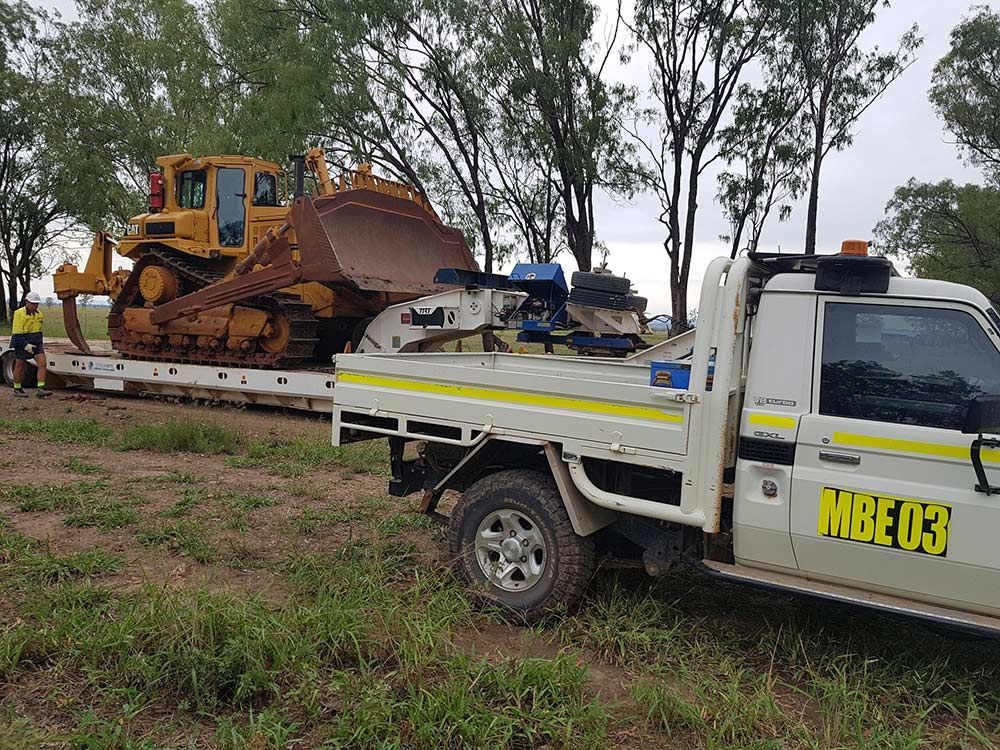 A Bulldozer Is Being Towed By A Tow Truck — Mike Barlow Earthmoving Pty Ltd in Rockhampton, QLD