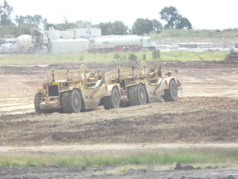 Two Excavator Working On Dirt Field With Trees In Background — Mike Barlow Earthmoving Pty Ltd in Rockhampton, QLD