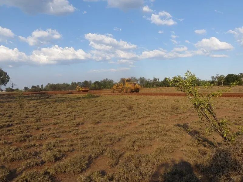 Dirty Road With Excavator Driving On It — Mike Barlow Earthmoving Pty Ltd in Rockhampton, QLD