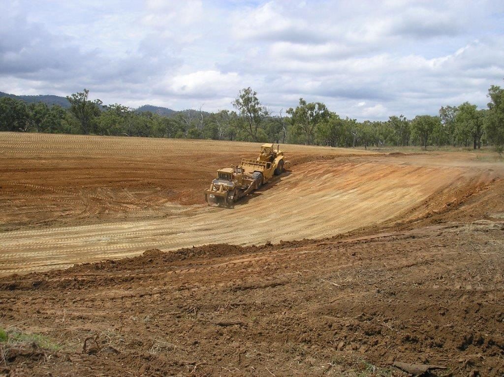 A Yellow Bulldozer Is Unloading Dirt Into a Pile — Mike Barlow Earthmoving Pty Ltd in Rockhampton, QLD
