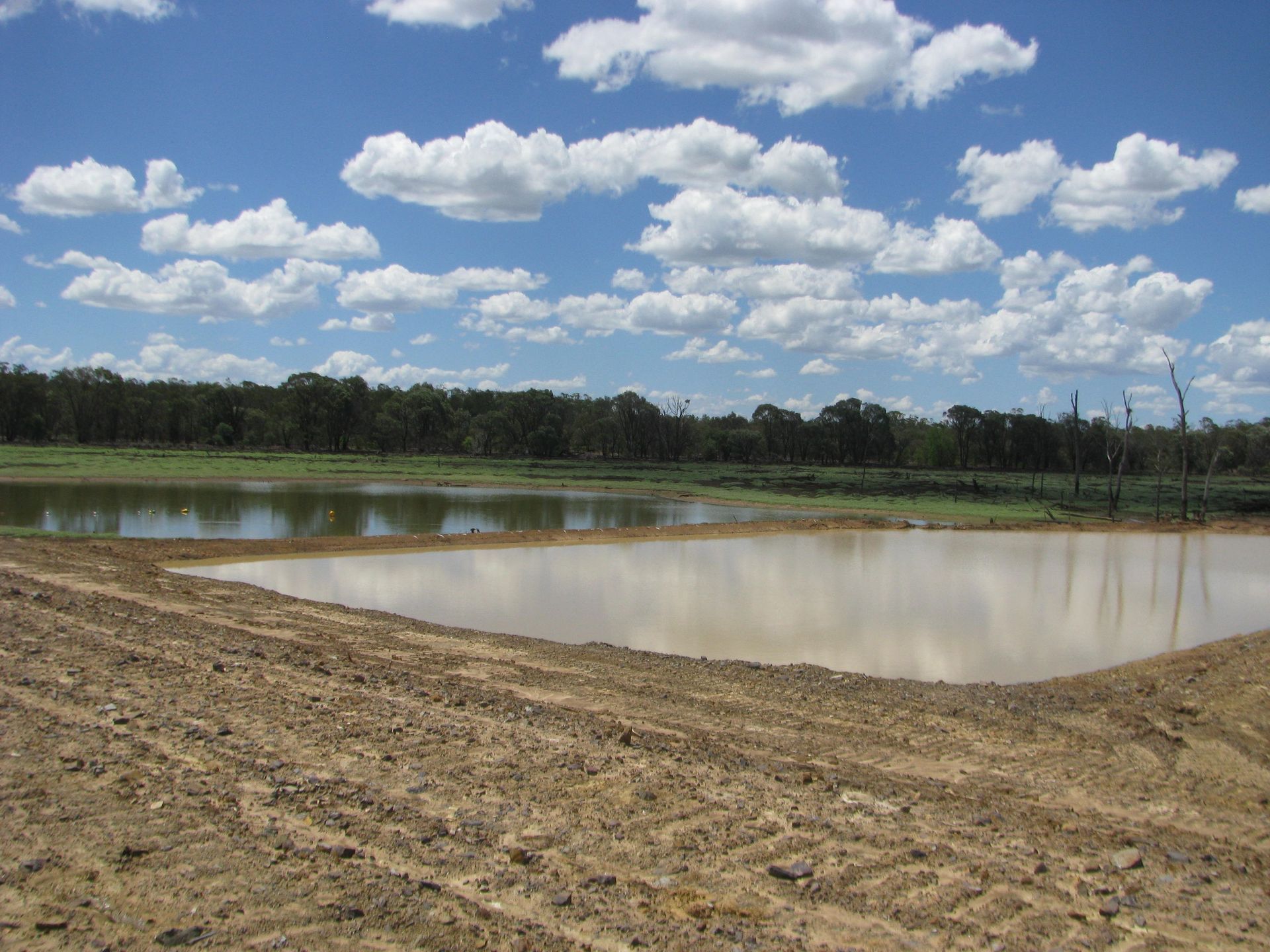 A Row of Construction Vehicles Are Parked in A Dirt Lot — Mike Barlow Earthmoving Pty Ltd in Rockhampton, QLD