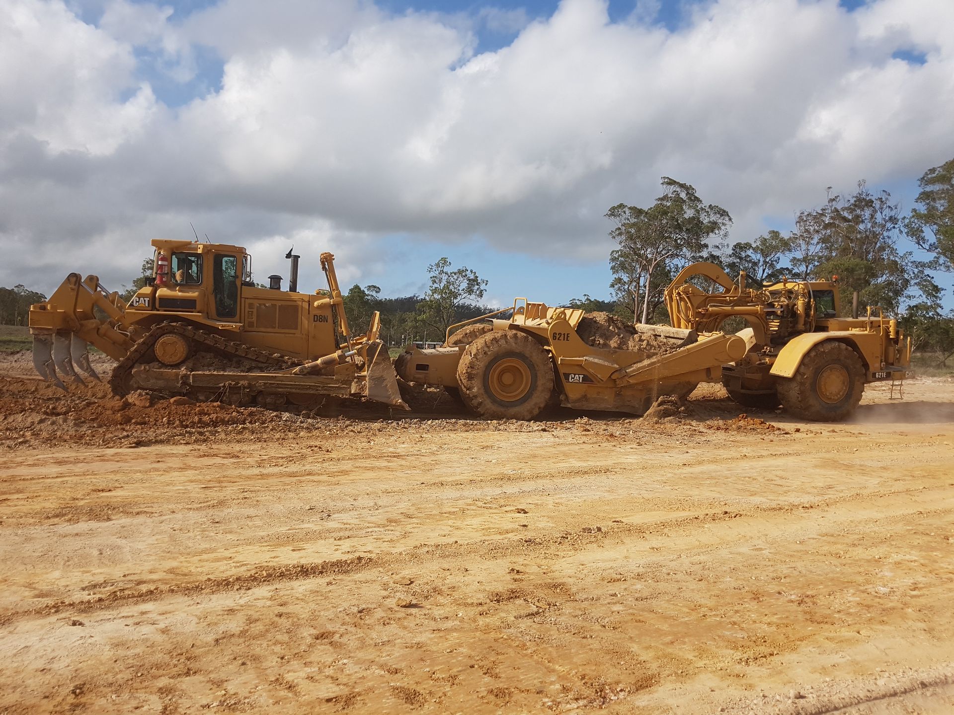 A Large Yellow Dump Truck Is Driving Through a Grassy Field — Mike Barlow Earthmoving Pty Ltd in Central Highlands, QLD