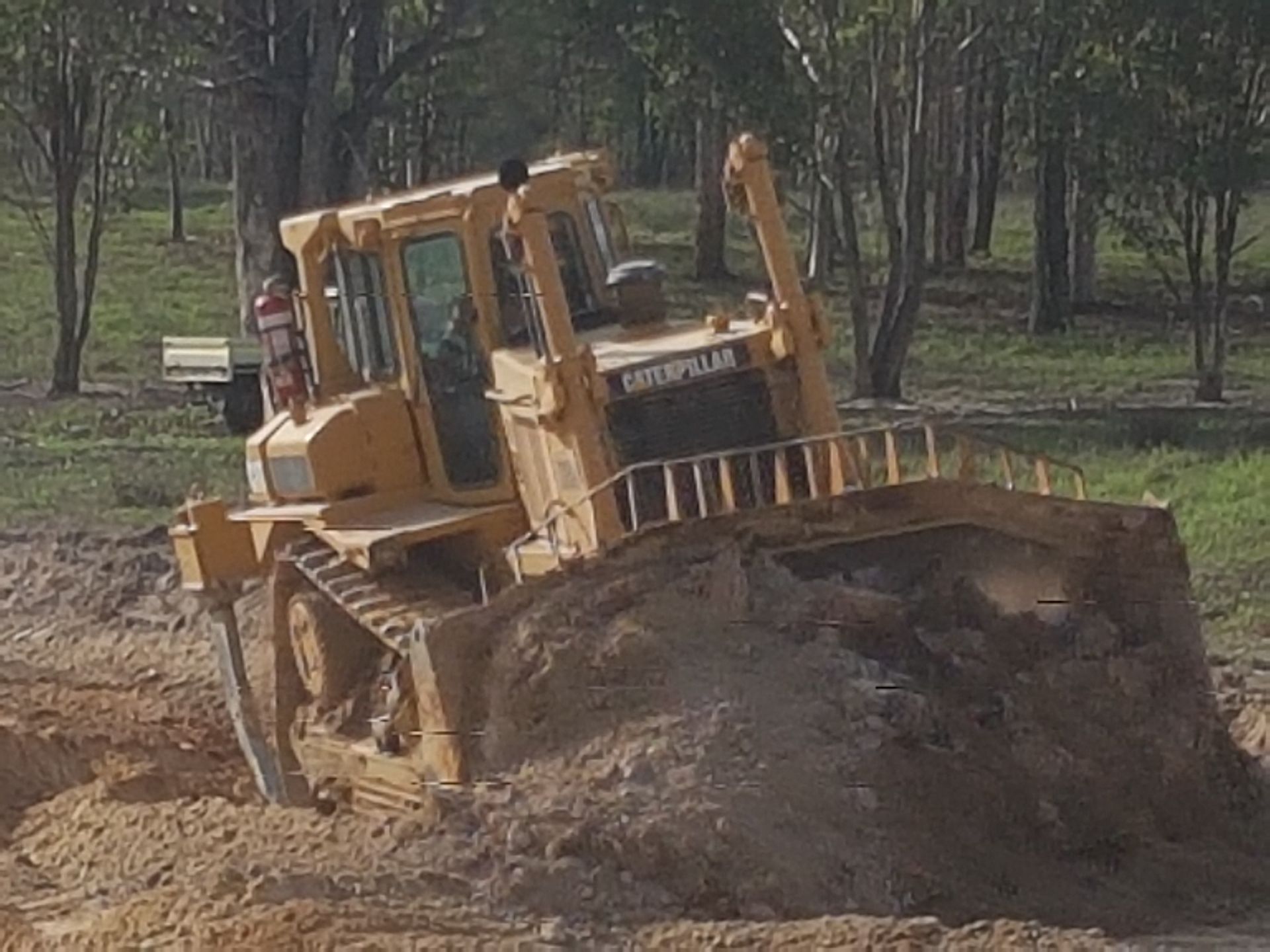 Two Bulldozers Are Driving Through A Large Dirt Field — Mike Barlow Earthmoving Pty Ltd in Rockhampton, QLD