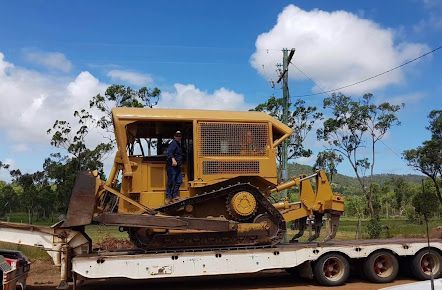 A Bulldozer Is Towed on Top of A Trailer Truck — Mike Barlow Earthmoving Pty Ltd in Rockhampton, QLD