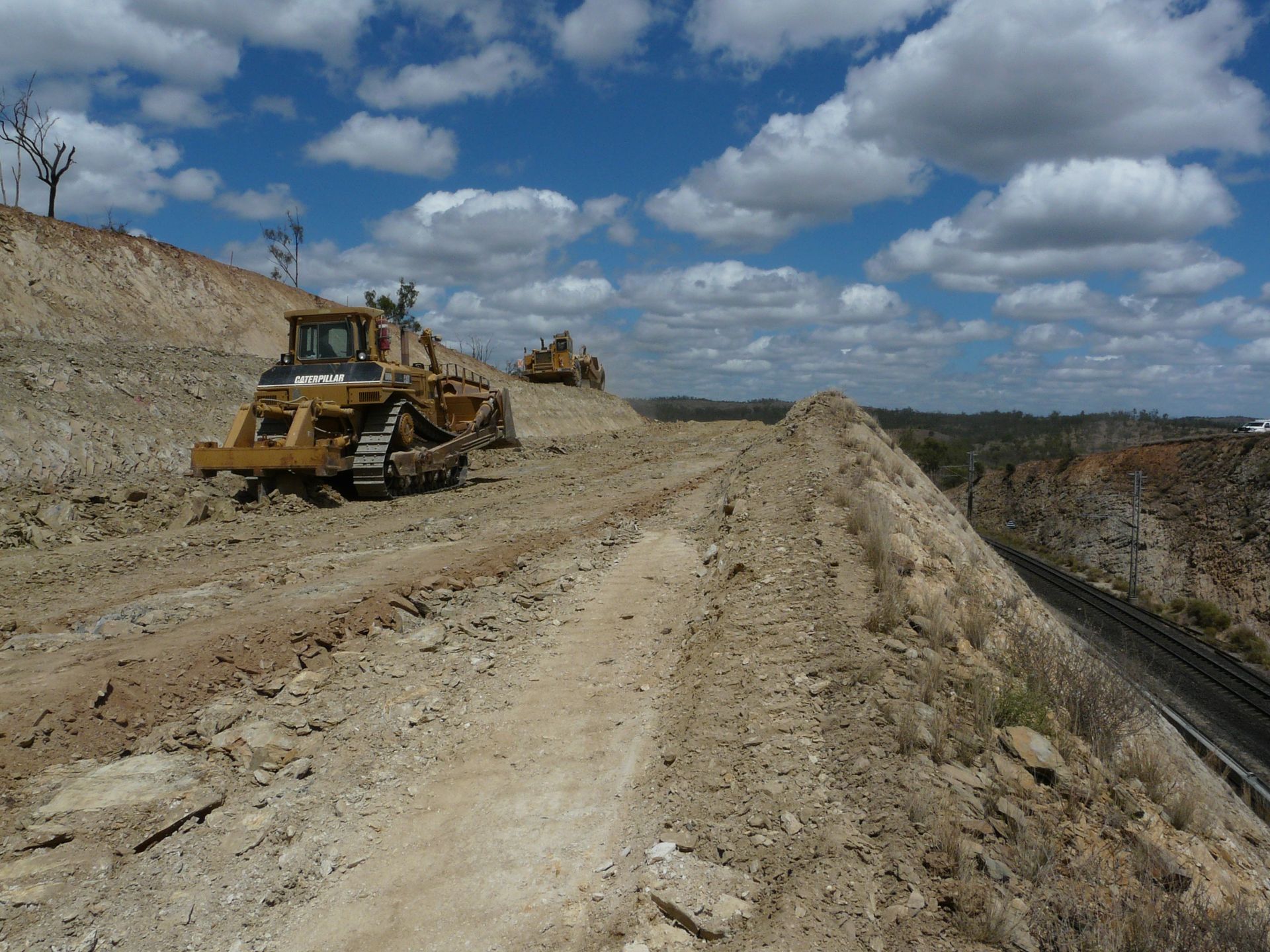 A Yellow Excavator Is Working on A Construction Site — Mike Barlow Earthmoving Pty Ltd in Central Highlands, QLD