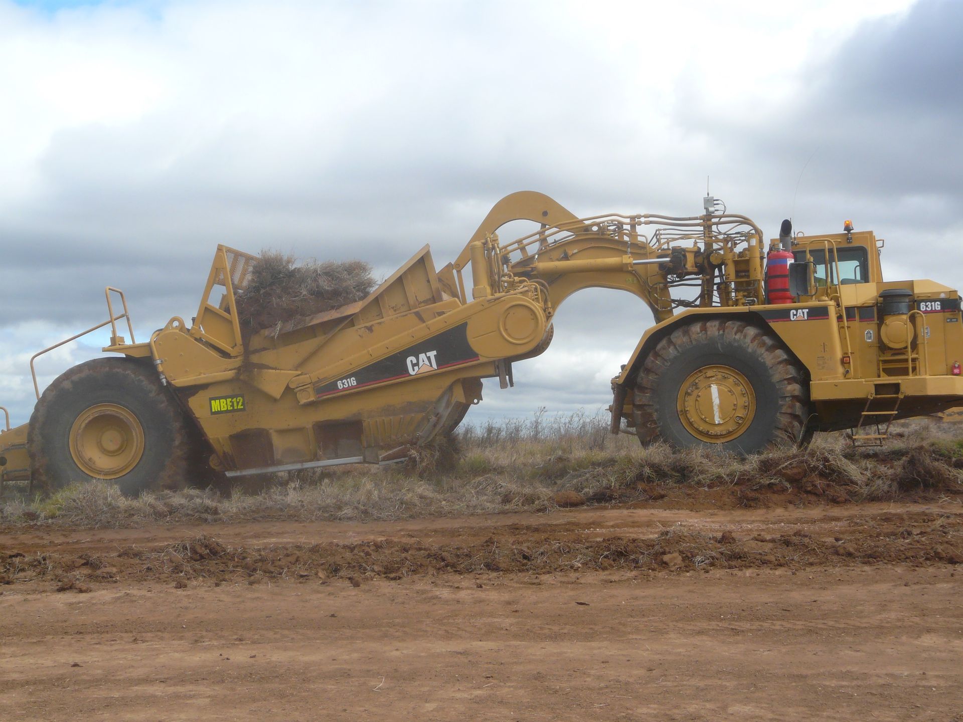 A Bulldozer Is Being Transported on A Trailer on A Dirt Road — Mike Barlow Earthmoving Pty Ltd in Gladstone, QLD