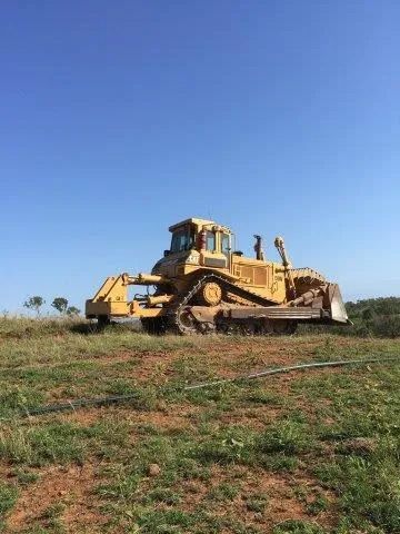 A Bulldozer Is Parked in The Middle of A Grassy Field — Mike Barlow Earthmoving Pty Ltd in Rockhampton, QLD