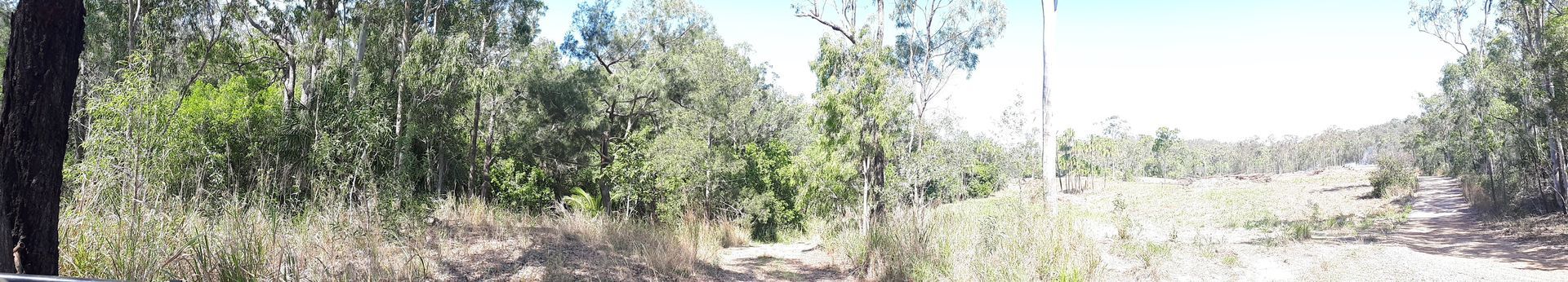 A Large Yellow Tractor Is Parked on The Middle of A Dirt Field — Mike Barlow Earthmoving Pty Ltd in Rockhampton, QLD