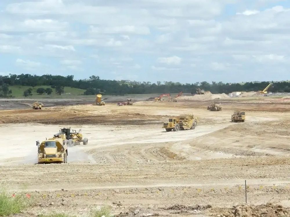 A Group of Construction Vehicles Are Working on A Dirt Road — Mike Barlow Earthmoving Pty Ltd in Rockhampton, QLD
