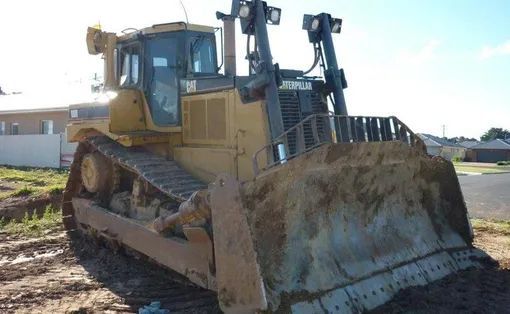 A Large Bulldozer Is Parked In A Dirt Field — Mike Barlow Earthmoving Pty Ltd in Rockhampton, QLD