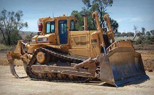 A Bulldozer Is Parked on The Side of A Dirt Road — Mike Barlow Earthmoving Pty Ltd in Gladstone, QLD
