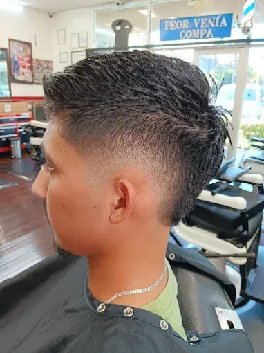 Man with a faded haircut in a barbershop. He has dark hair styled up and a low fade along his sides.