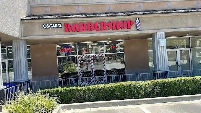 Oscar's Barbershop with red signage above a storefront, featuring an open door and a barber pole, in a strip mall.