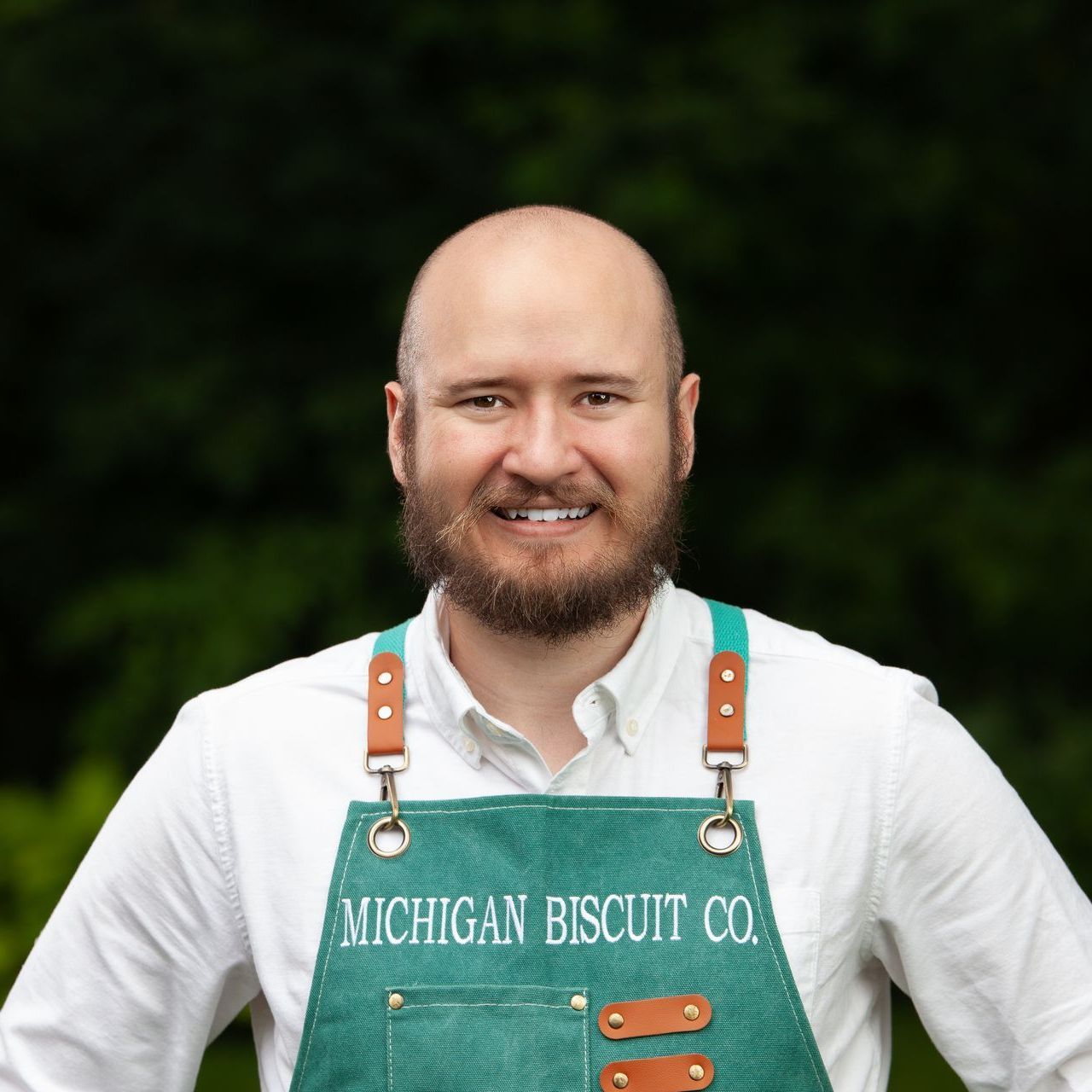 A bald man with a beard wearing a Michigan Biscuit Co. apron