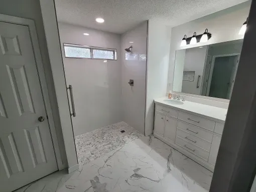 A bathroom with a walk in shower , sink and mirror.