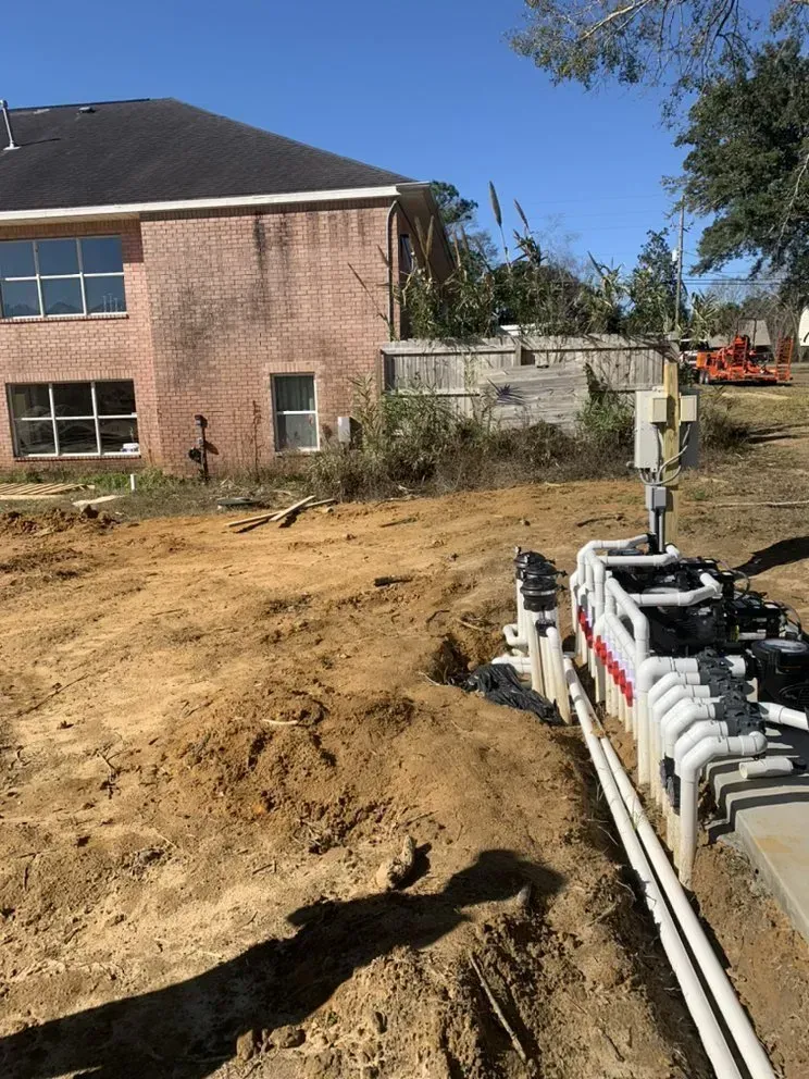 A house with a lot of pipes in the dirt in front of it