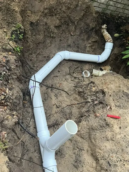 A bunch of white pipes are laying in the dirt.