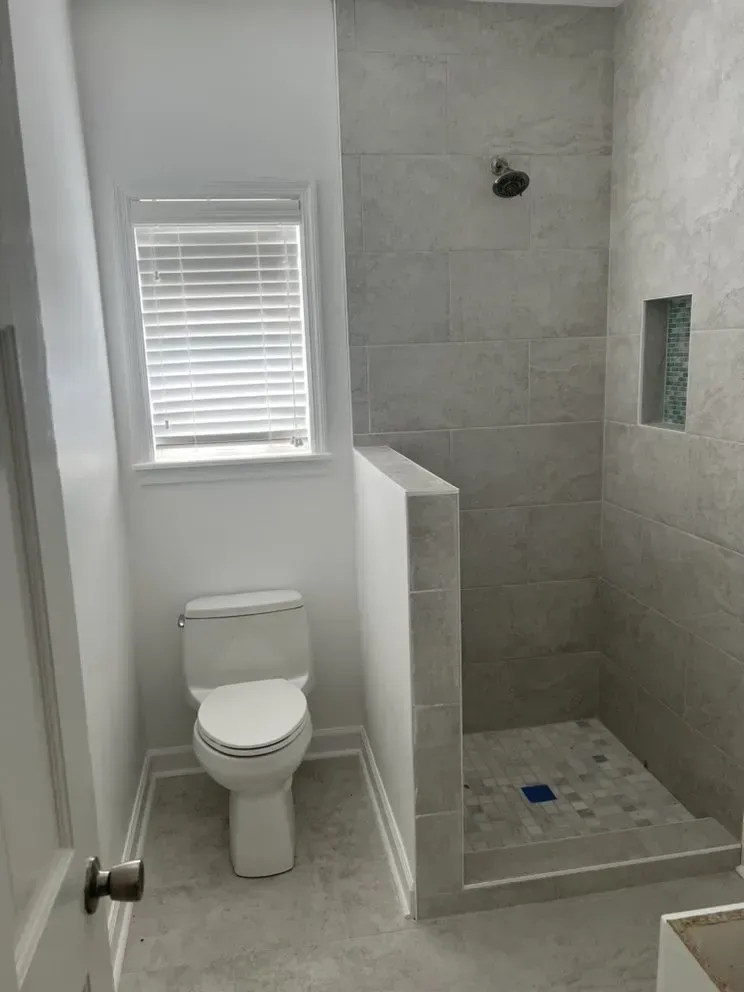 A bathroom with a toilet and a walk in shower.