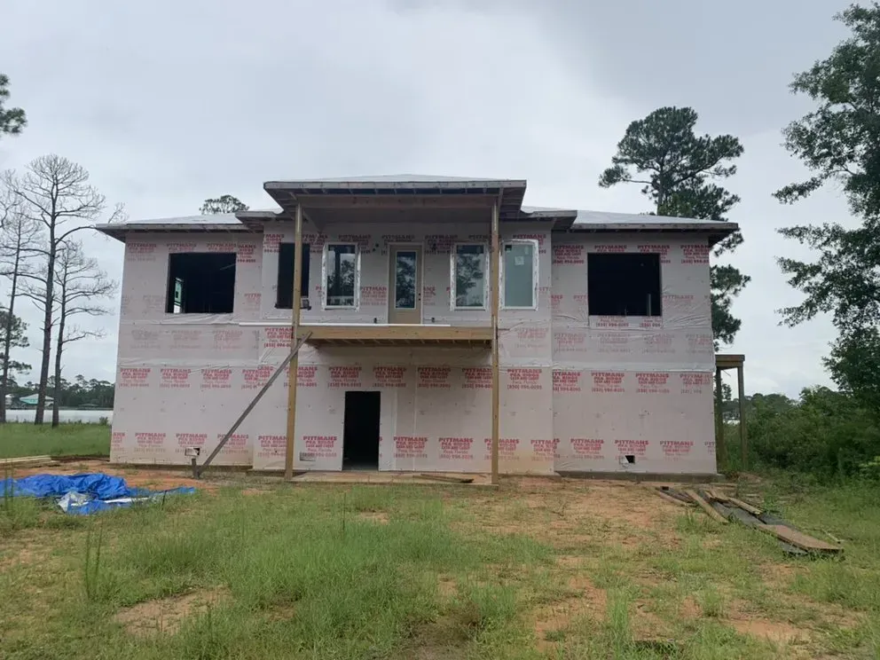 A large house is being built in the middle of a grassy field.