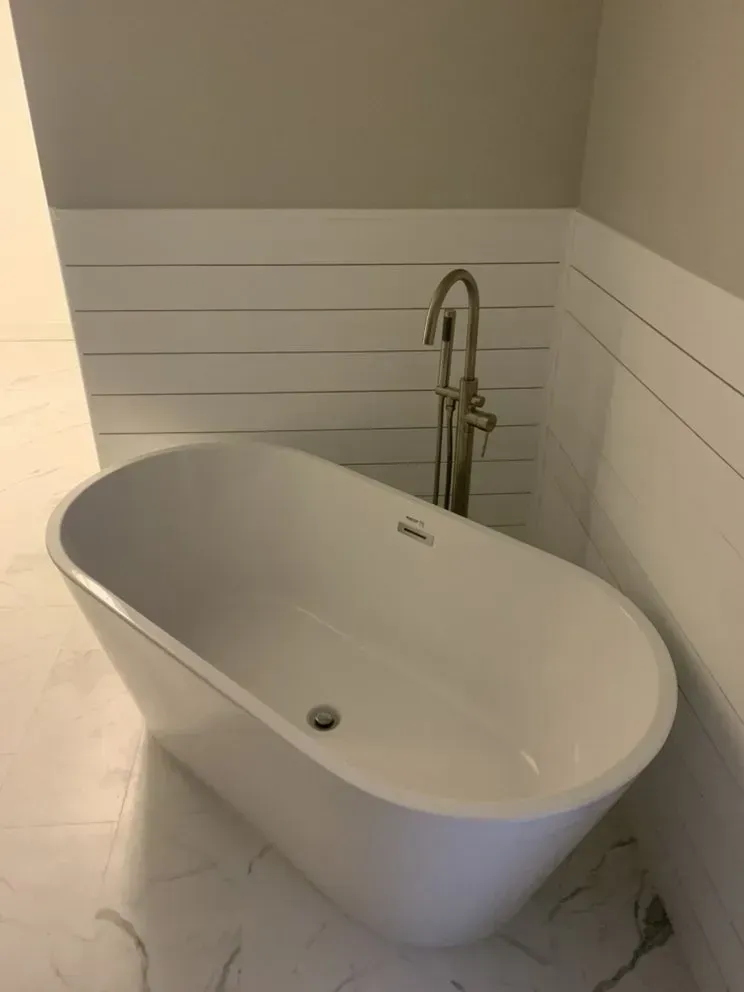 A white bathtub is sitting in a bathroom next to a faucet.