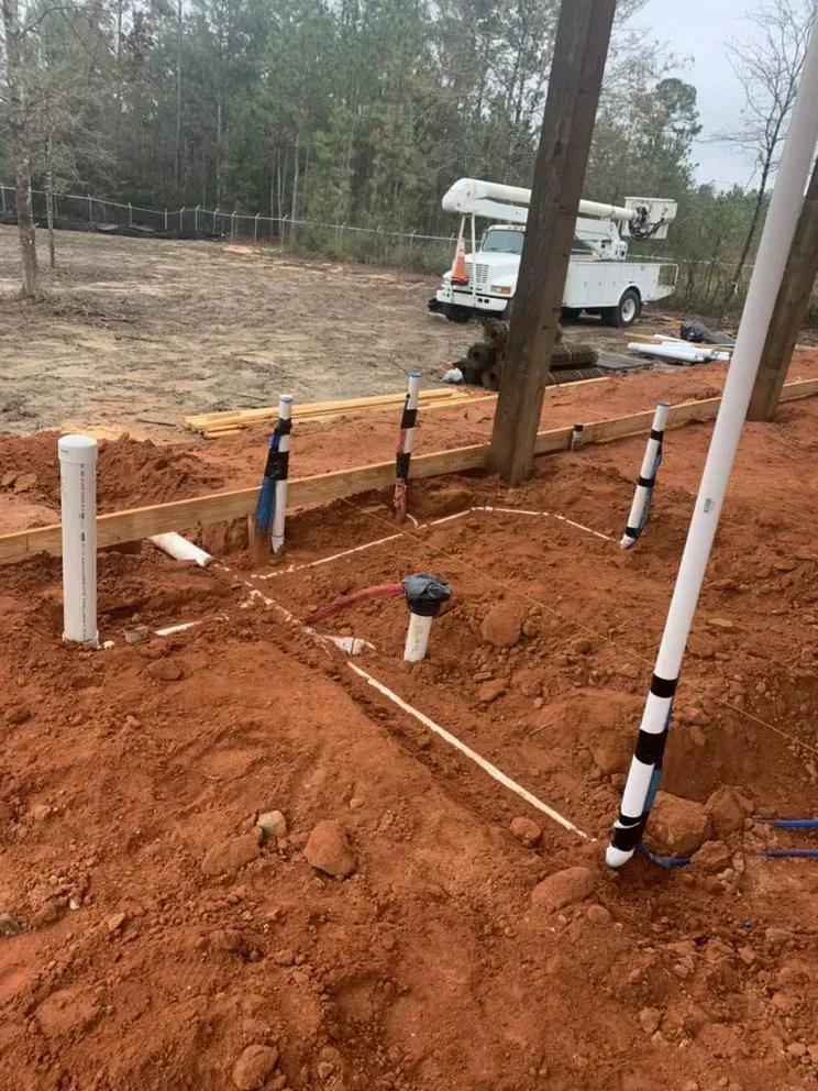 A white truck is parked in the dirt next to a fence.