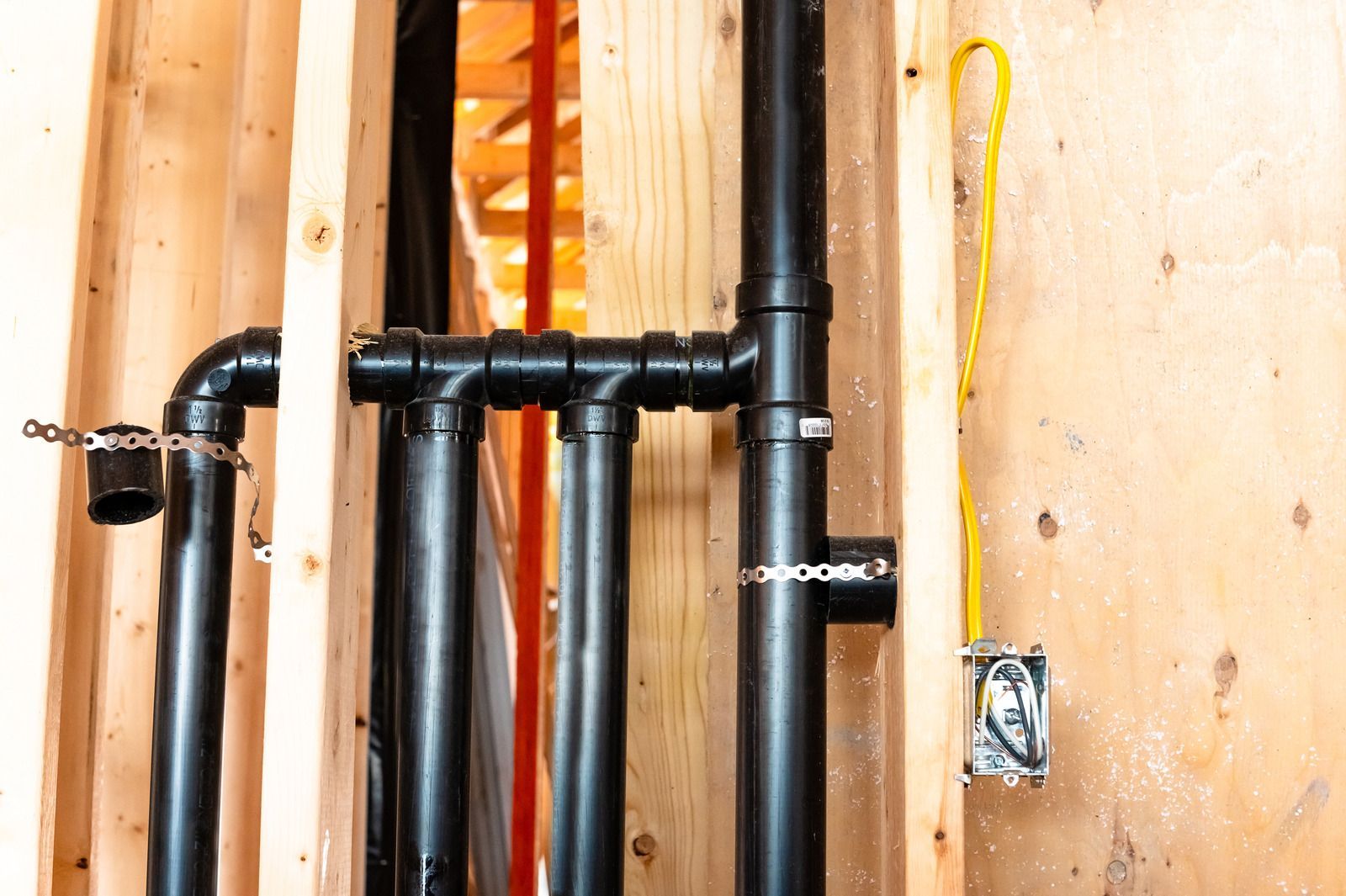 A bunch of black pipes are hanging on a wooden wall.