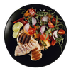 Grilled chicken and salad with tomatoes, red onion, and lime on a black plate.