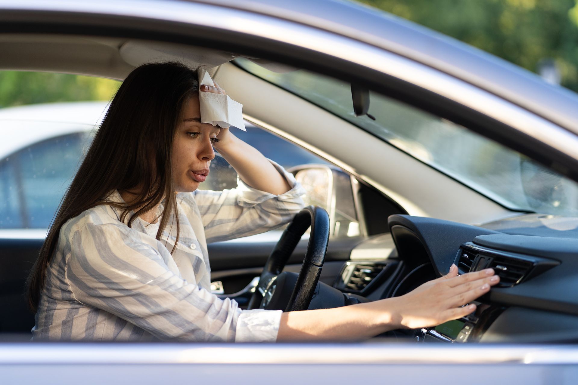 A woman is sitting in a car with a towel on her head.