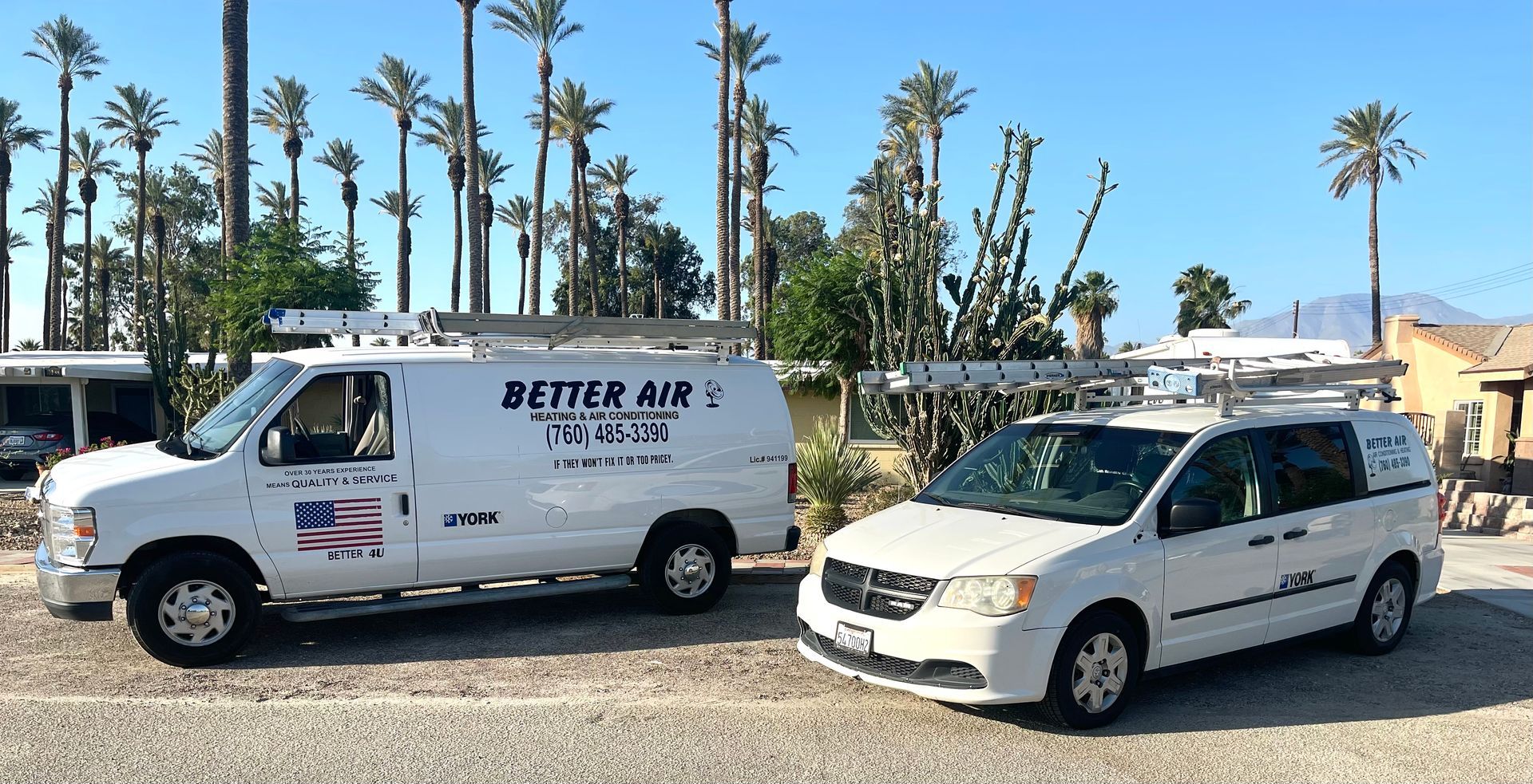 Two white vans are parked next to each other in a parking lot.