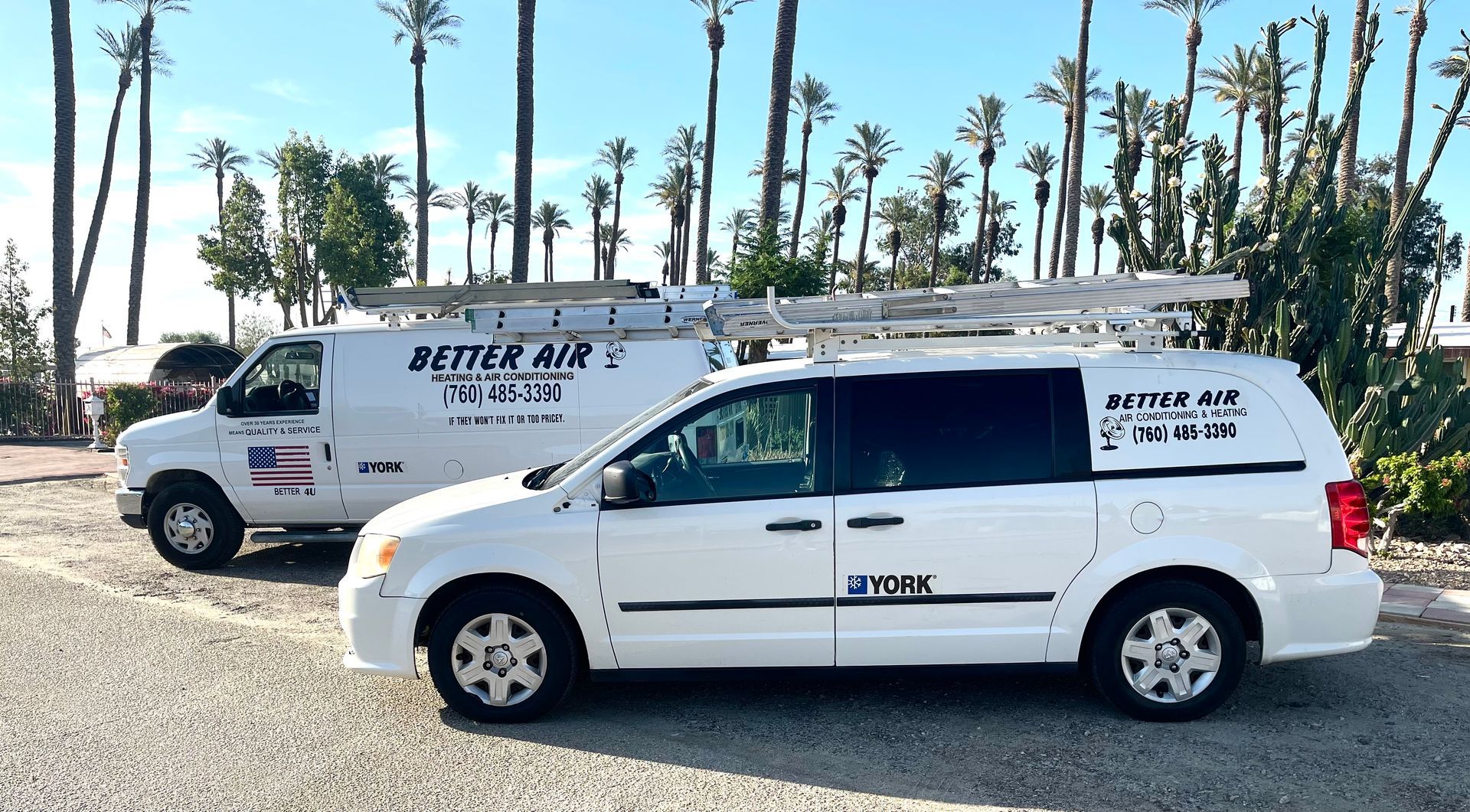Two white vans are parked next to each other in a parking lot.