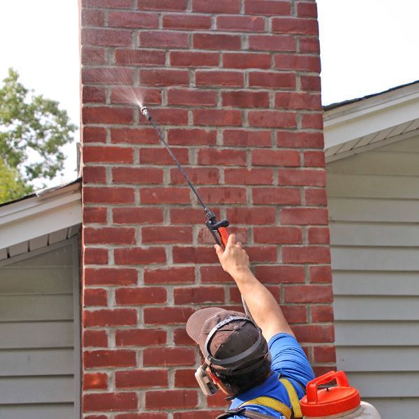 A man spraying a brick wall with a sprayer